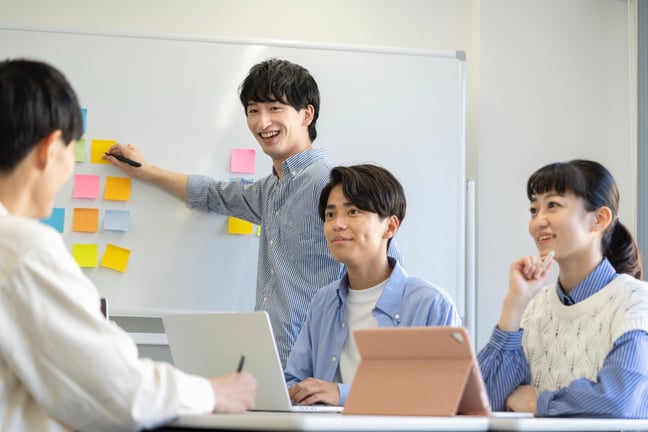 明るい会議室で、付箋やワークシートを使いながら笑顔でディスカッションを行う参加型社内研修のイメージ