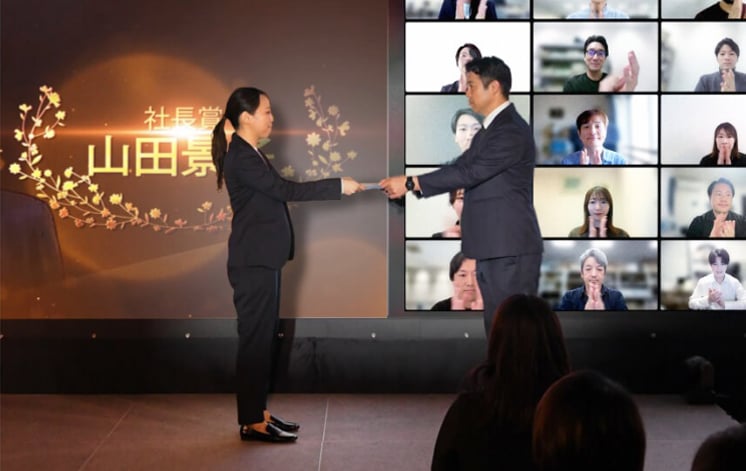 活躍した社員が社内表彰式でトロフィーを受け取る様子