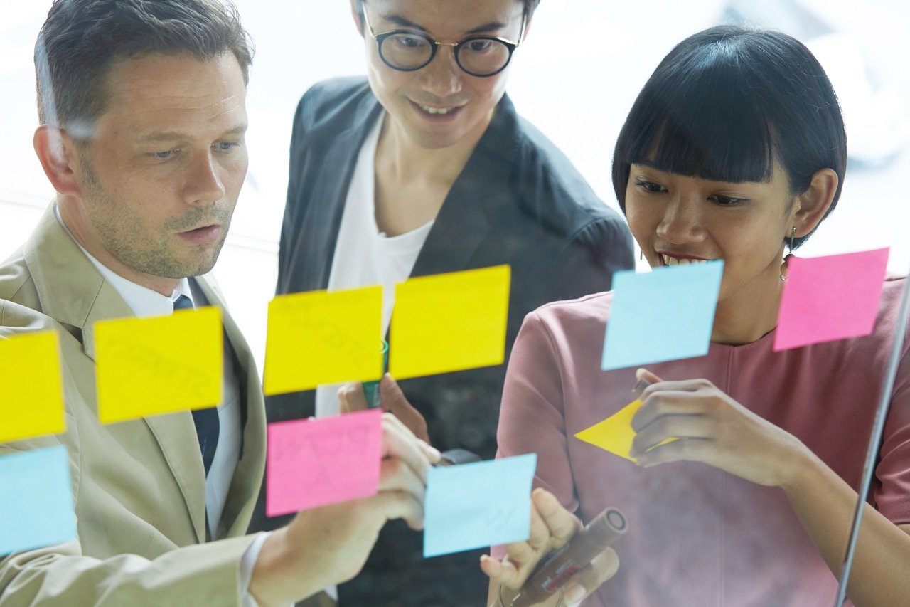 ホワイトボードに付箋を貼り出し、デザイン思考のプロセスで課題解決のアイデアを出すワークショップの光景