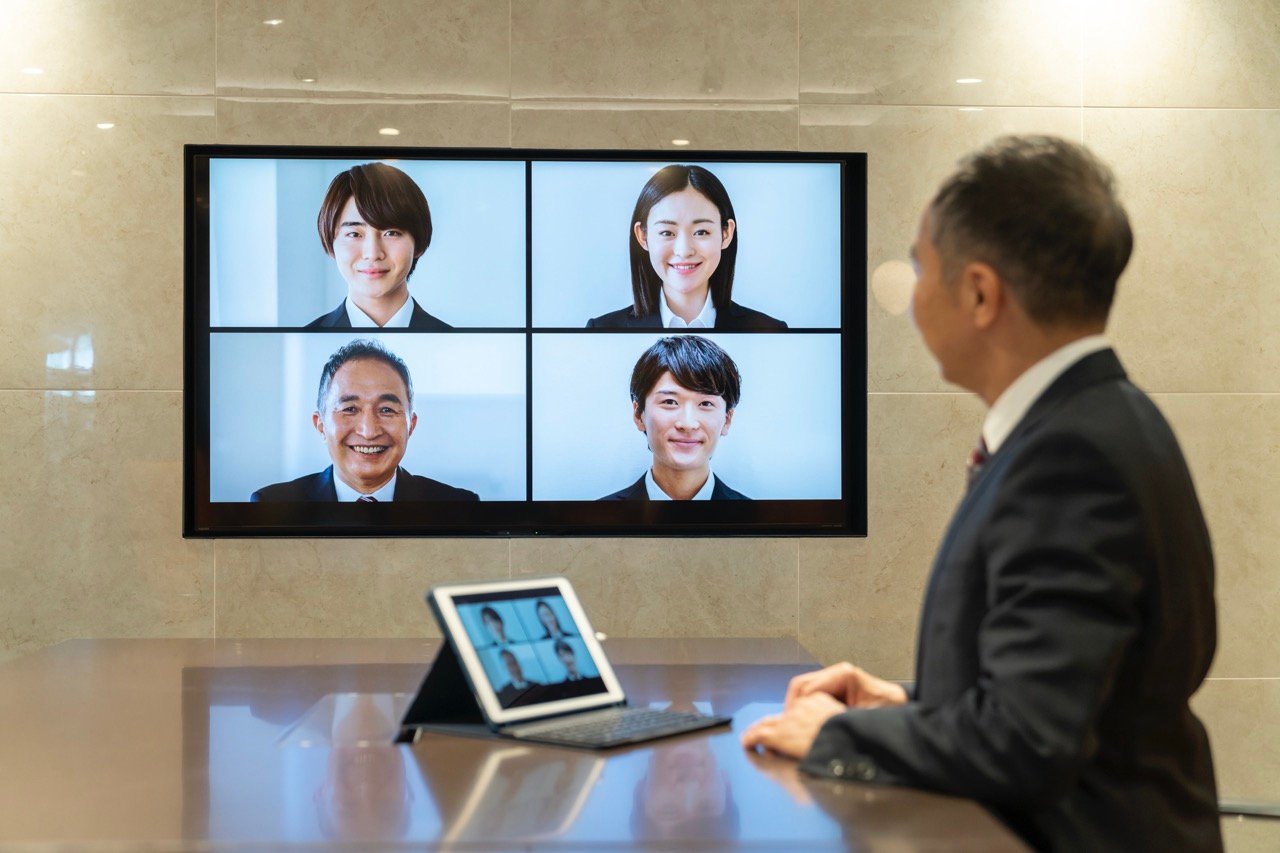 自宅からPCでオンライン内定式に参加する内定者と、オフィスから配信する人事担当者