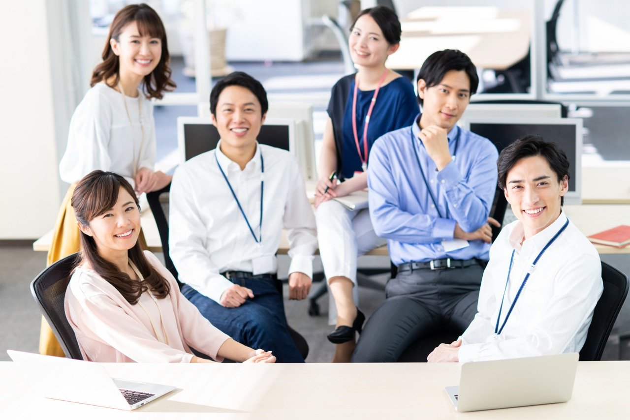 社内懇親会の実施によって職場内の心理的安全性が高まり、部署間の壁が取り除かれた活気あるオフィス環境のイメージ